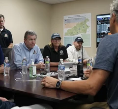 North Carolina Governor Roy Cooper, alomg with FEMA and state disaster recovery agency officials, get briefed by Mission Hospital CEO Greg Lowe on the impacts of the Hurricane Helene flooding on the main hospital in Ashville and what they need to continue operations. The hospital is operating, but is using water from trucks because the city water treatment facilities were damaged and contaminated during flooding. Photo North Carolina Governor's Office.