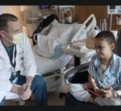 Douglas Overbey, MD, an assistant professor in the department of surgery at Duke University School of Medicine, checks in with 9-year-old Kensley Frizzell as she recovers from heart surgery. Image courtesy of Duke Health and Duke University School of Medicine.
