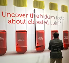 An attendee at AHA 2024 looking at educational displays on Lp(a) in the Novartis booth. Photo By Dave Fornell