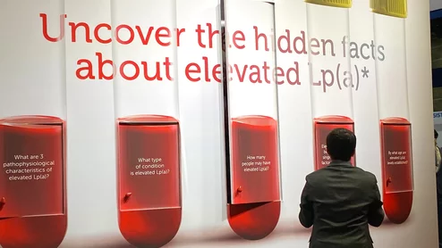An attendee at AHA 2024 looking at educational displays on Lp(a) in the Novartis booth. Photo By Dave Fornell